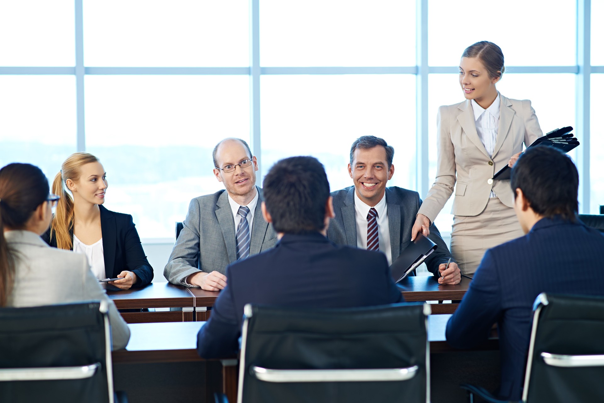 Shareholders having a meeting, a secretary giving out folders with documents